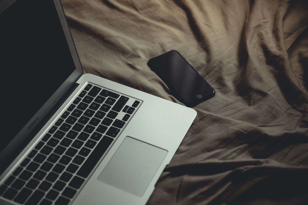Celular y laptop sobre cama