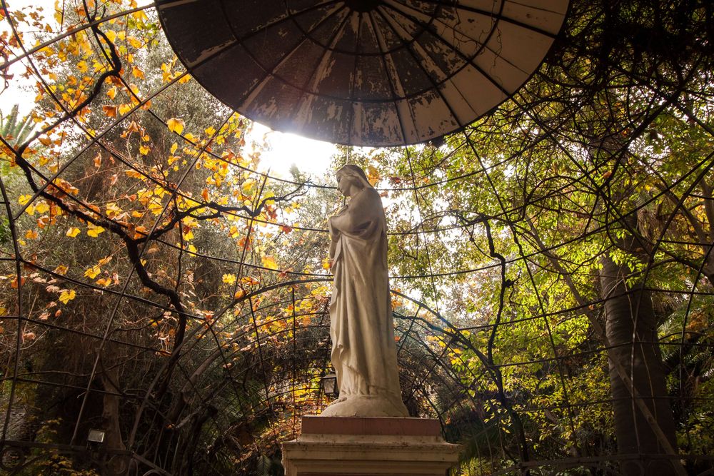 Una estatua de una santa bajo una cúpula en medio del bosque.